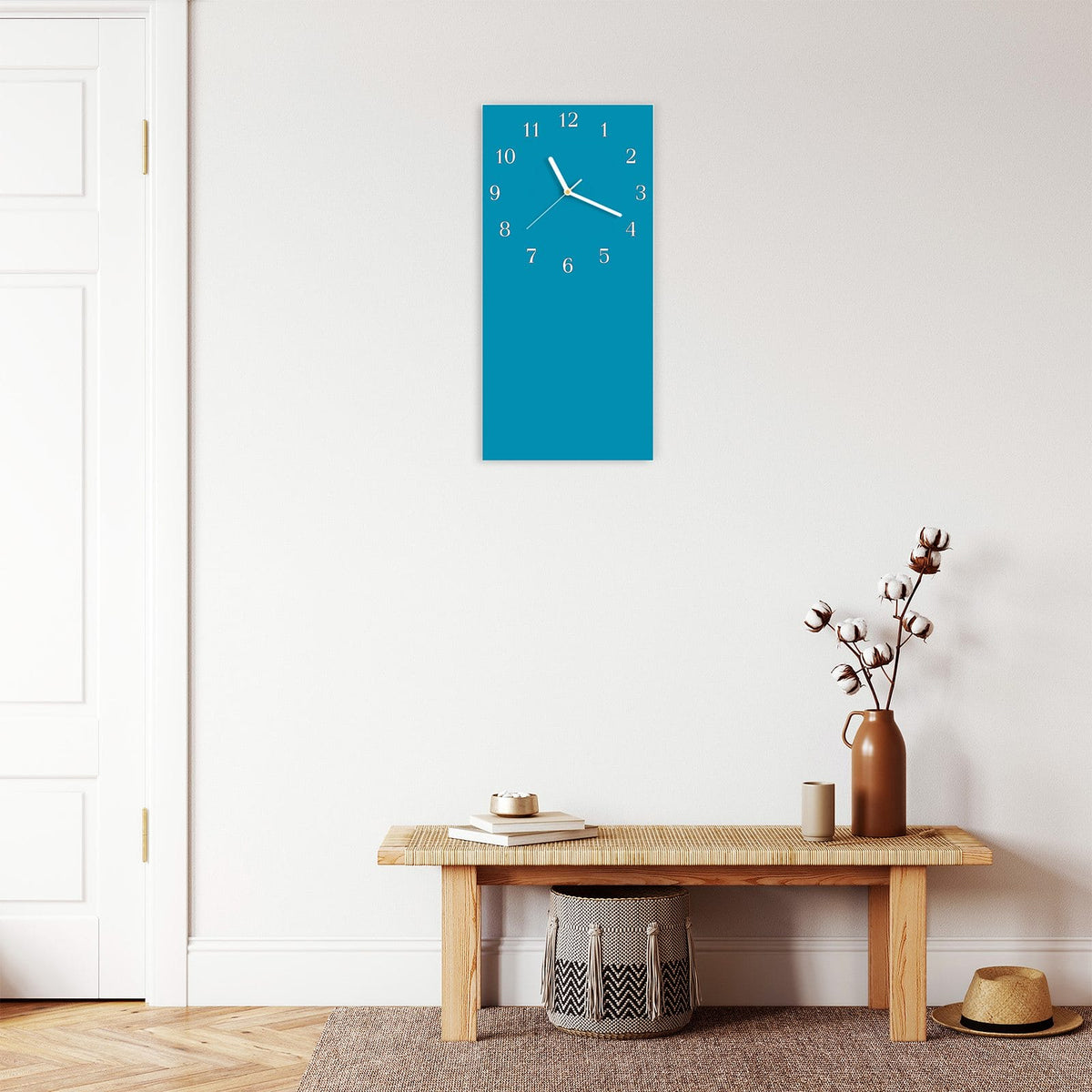 Wanduhr aus Glas im Hochformat Petrolblau mit Ziffernblatt Klassisch über einer Holzbank im Flur