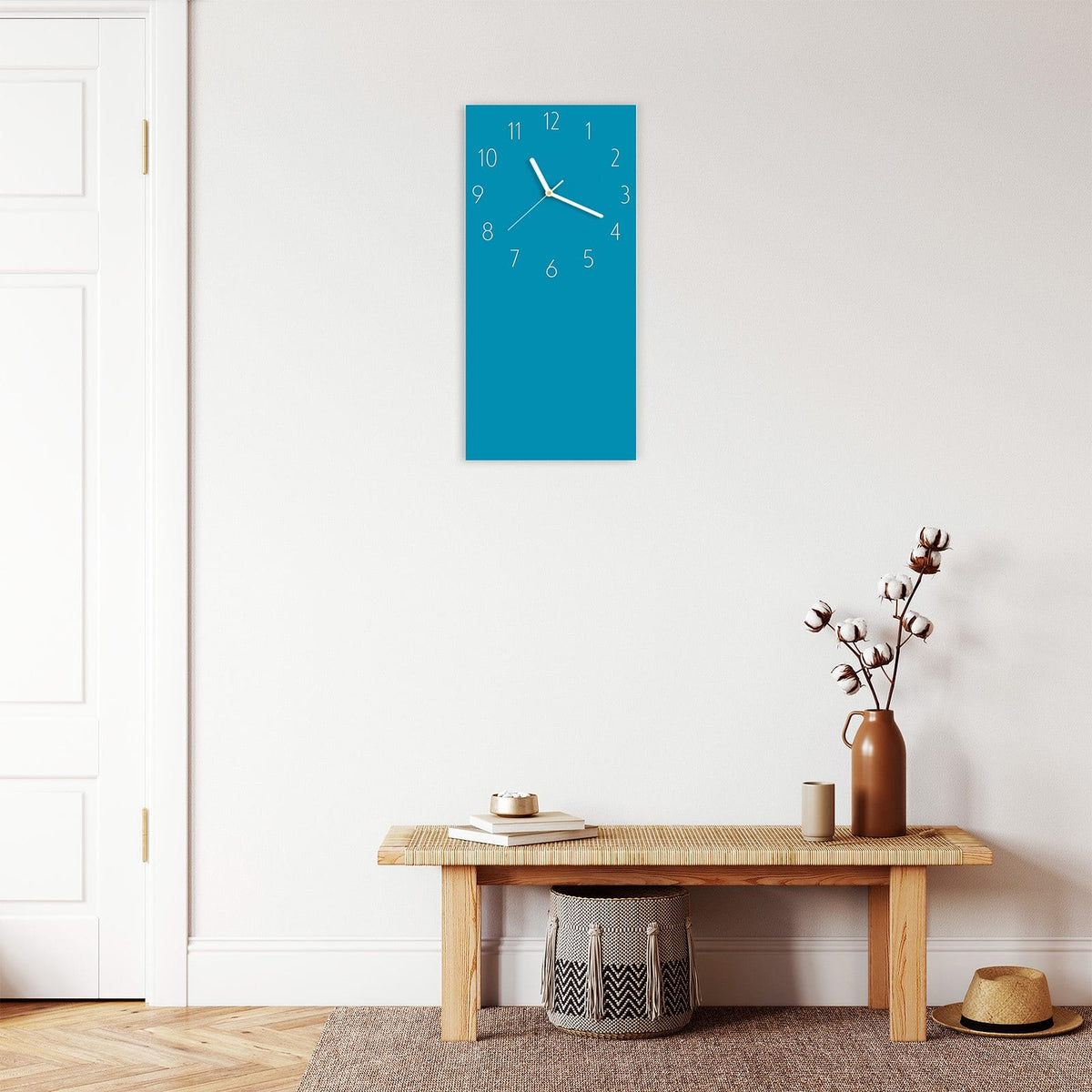 Wanduhr aus Glas im Hochformat Petrolblau mit Ziffernblatt Elegant über einer Holzbank im Flur