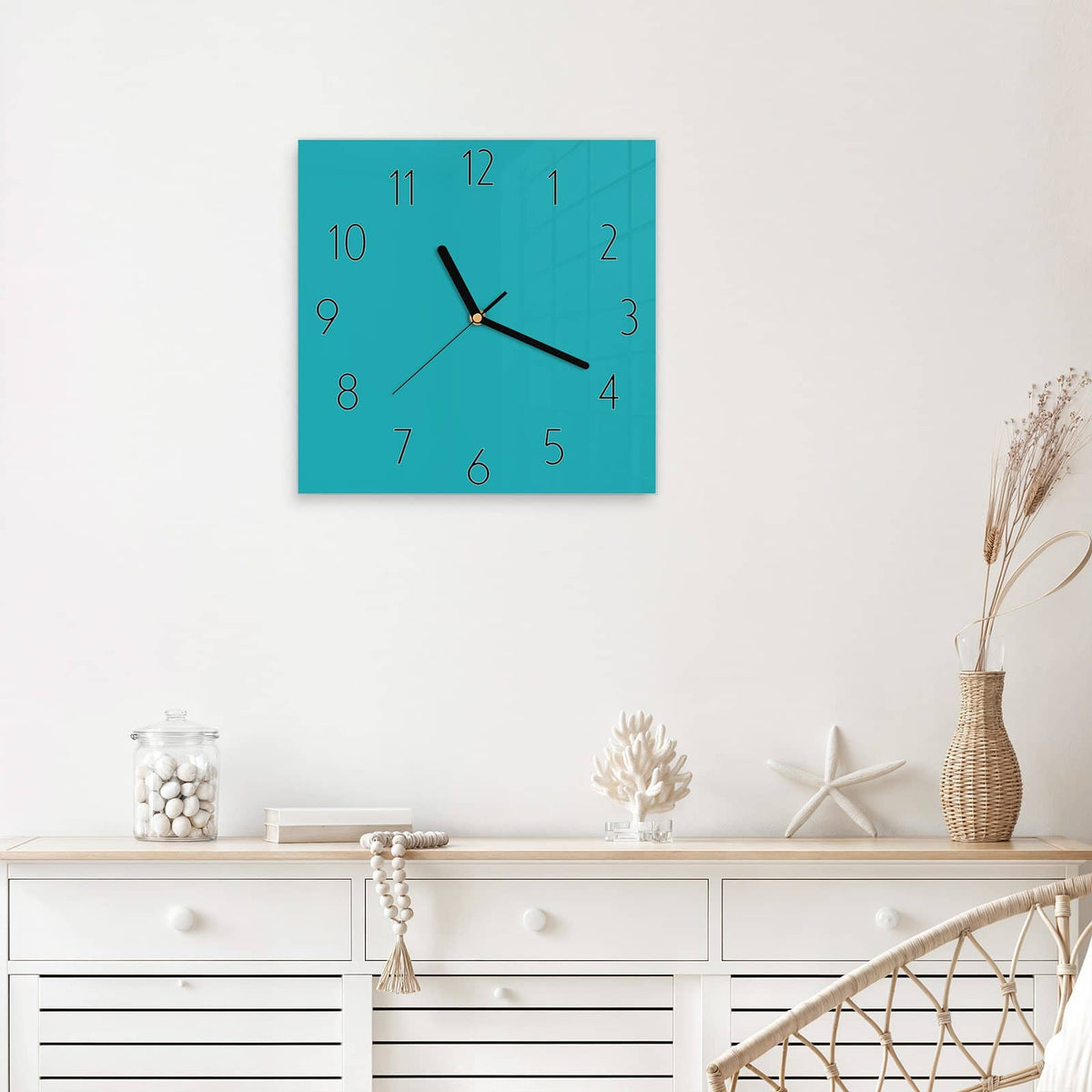 Quadratische Wanduhr aus Glas Lagunentürkis mit Ziffernblatt Elegant über einem weißen Sideboard