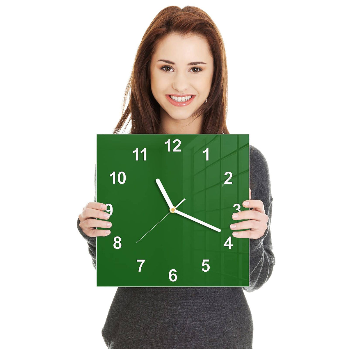 Quadratische Wanduhr aus Glas Waldgrün in zwei Händen gehalten – Größenvergleich, 30 × 30 cm