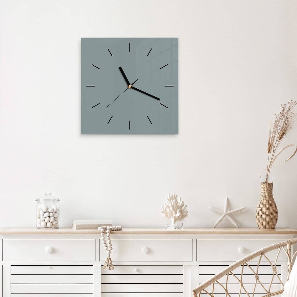 Quadratische Wanduhr aus Glas Steingrau mit Ziffernblatt Linie über einem weißen Sideboard