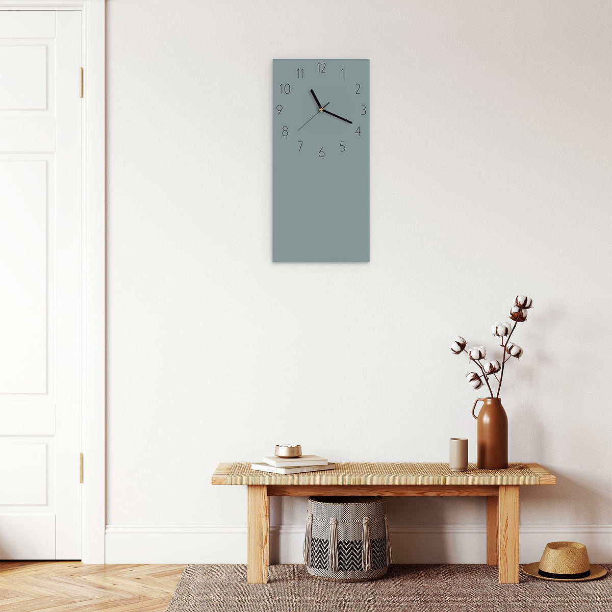 Wanduhr aus Glas im Hochformat Steingrau mit Ziffernblatt Elegant über einer Holzbank im Flur